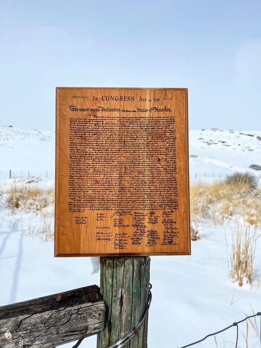 Declaration of Independence laser engraved on cherry on fence post in Wyoming landscape.  Wind River Outpost