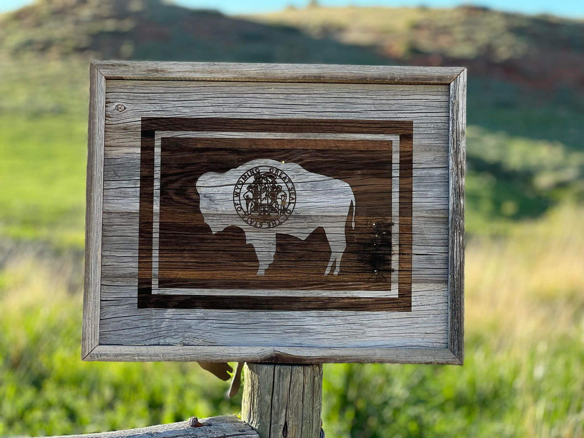 Wyoming Flag wall decor, made of rustic barnwood.  Size is 17&quot; x 21&quot;, displayed in photo with Wyoming landscape in background.