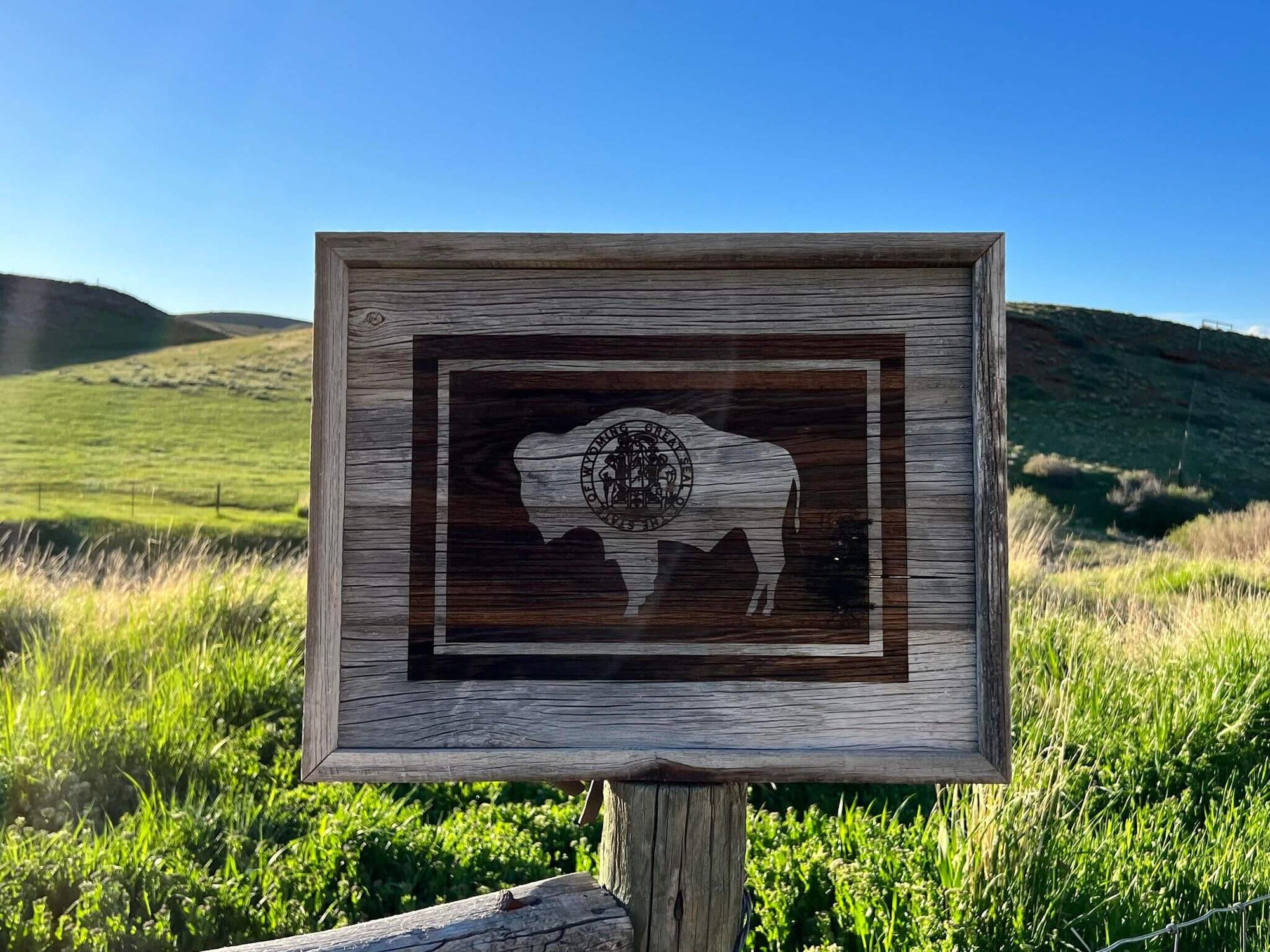 Wyoming Flag wall decor, made of rustic barnwood.  Size is 17" x 21", displayed in photo with Wyoming landscape in background