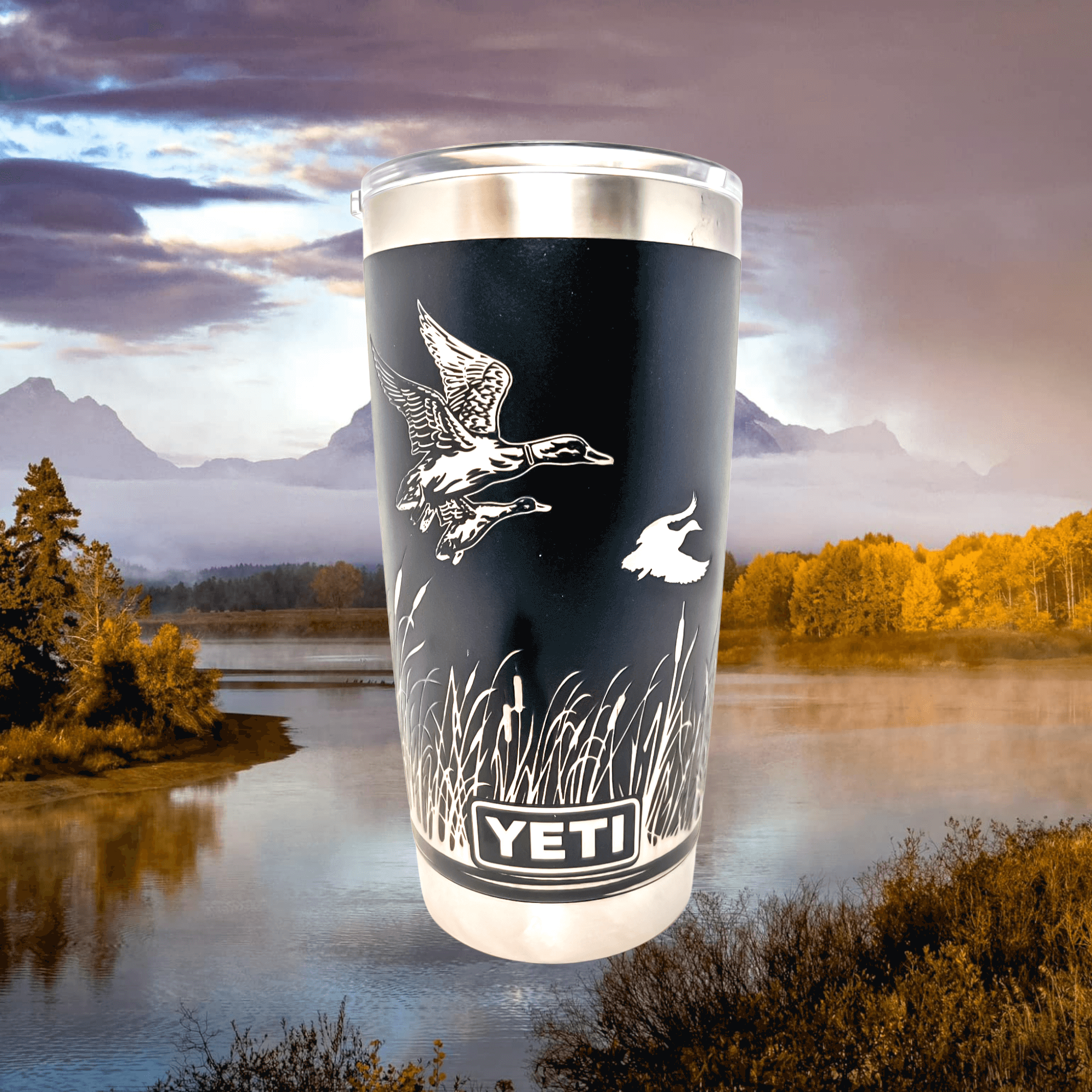 Alternate view of duck wrap Yeti tumbler with outdoor scene in background of photo