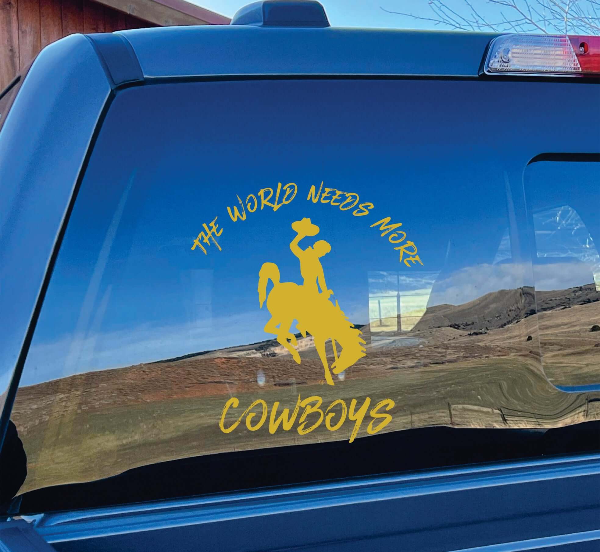 Photo of gold vinyl decal "World Needs More Cowboys" on car window